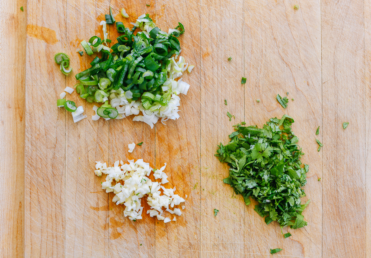 chopped scallions, garlic, and cilantro on cutting board