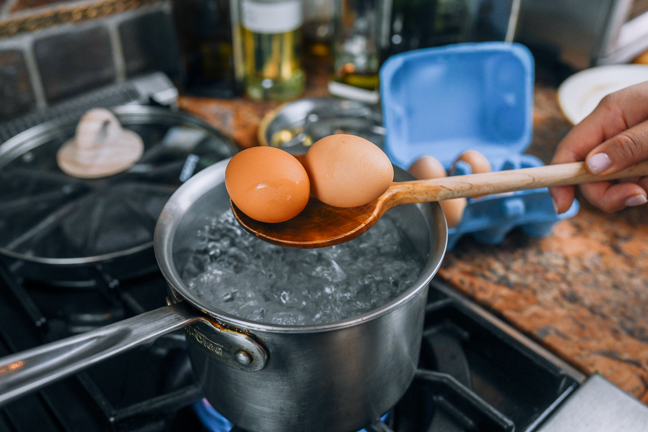 Lowering eggs into boiling water with a wooden spoon