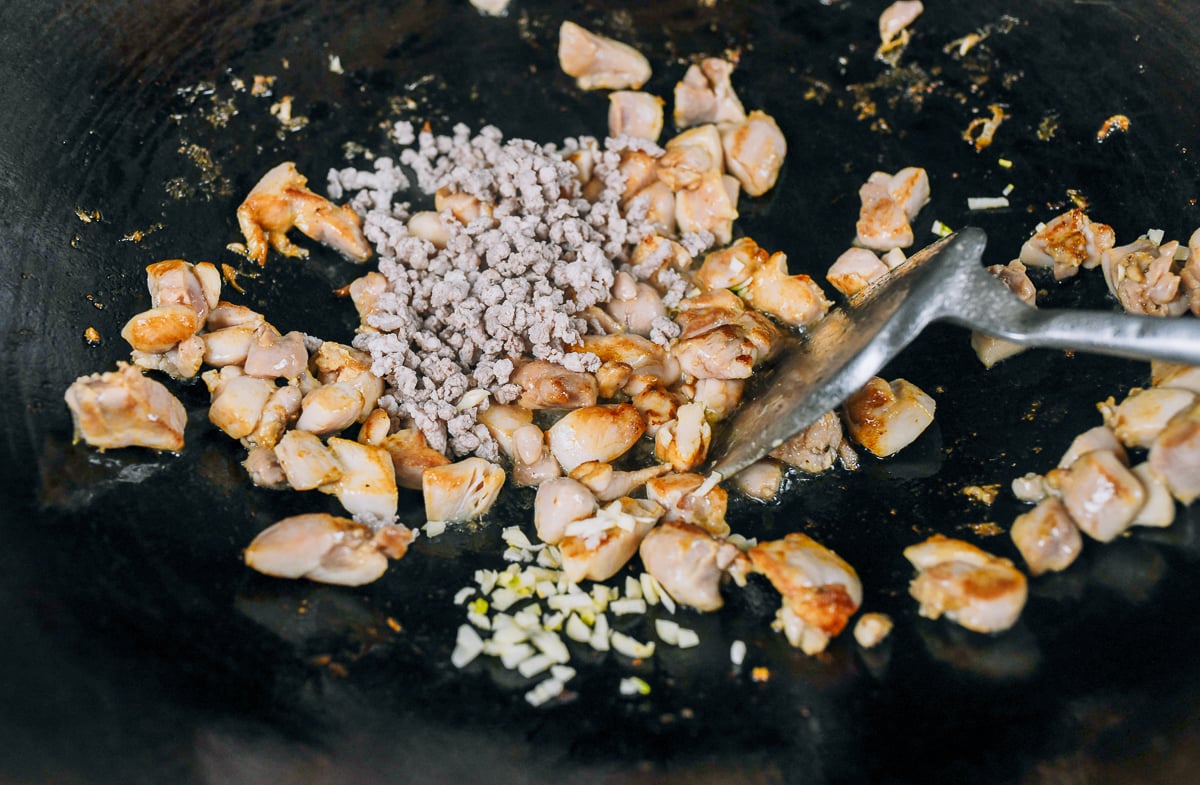 adding garlic and ground pork to seared chicken