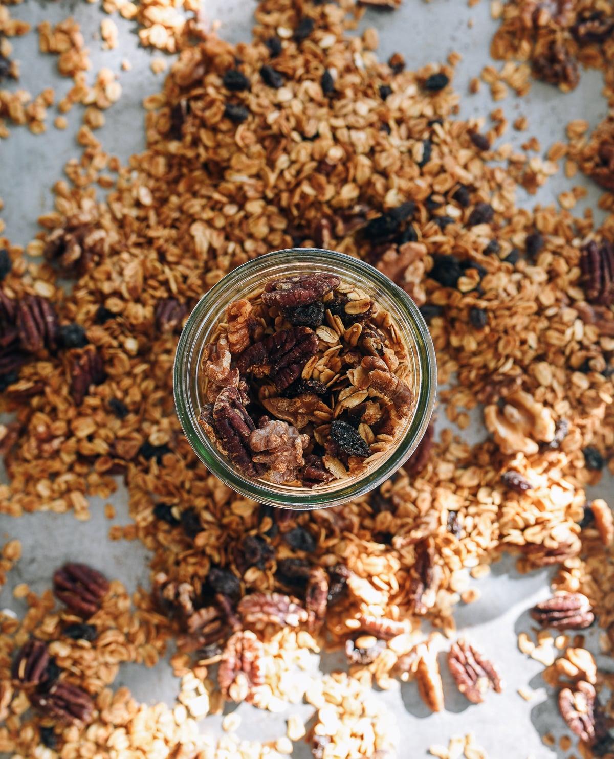 moving homemade granola from baking sheet to mason jar