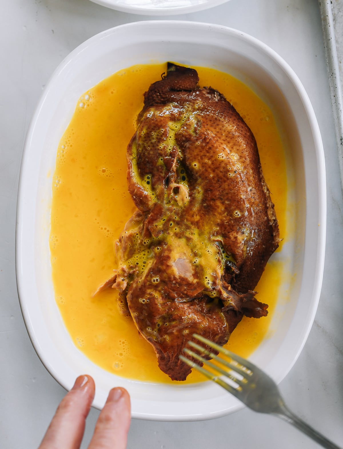 dipping de-boned duck half into beaten egg