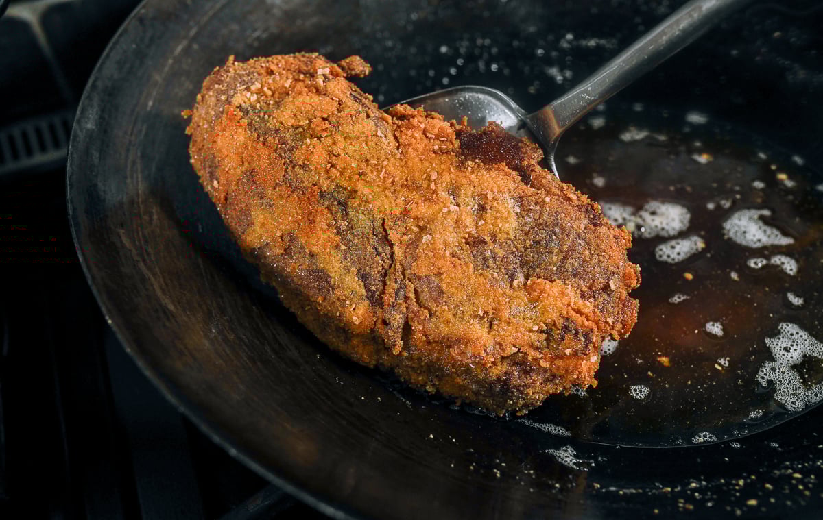 fried piece of boneless pressed duck coming out of wok