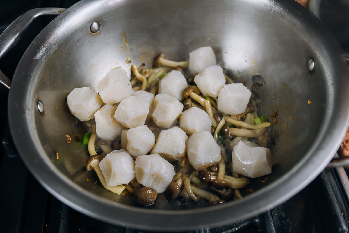 adding fish balls to pot with mushrooms