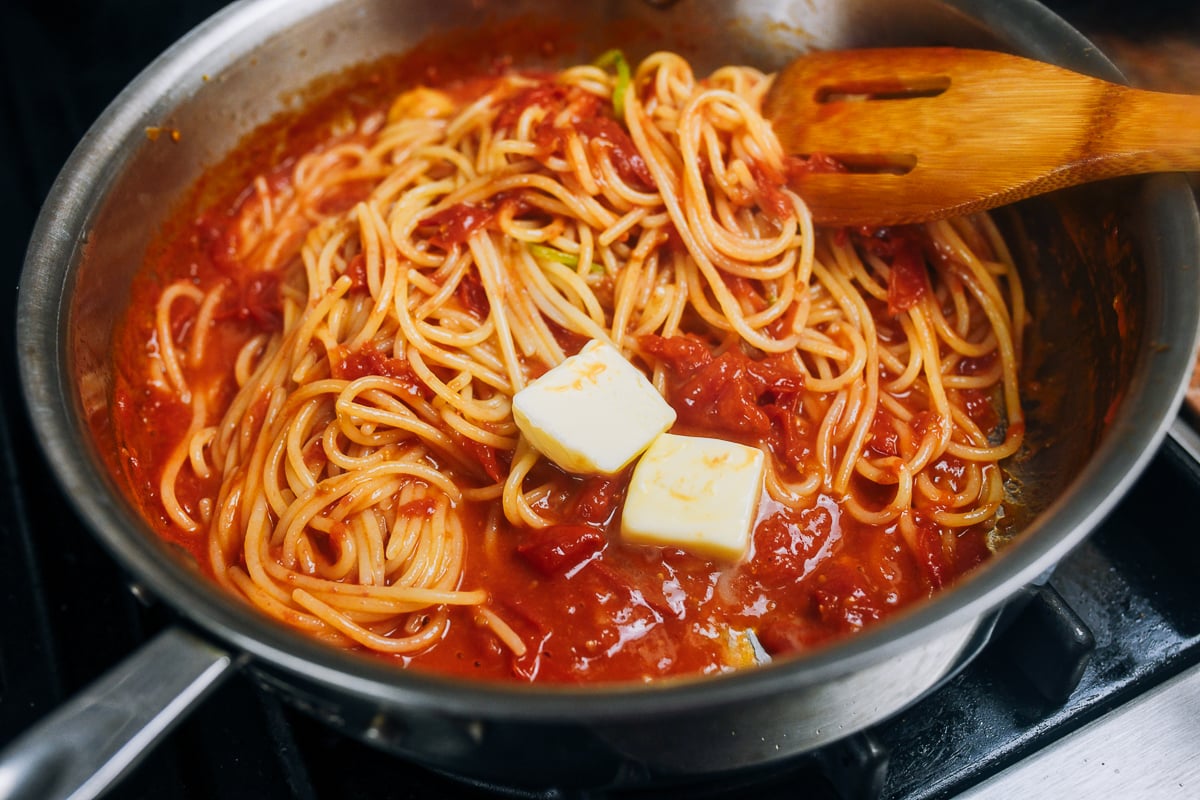 mixing two tablespoons of butter into spaghetti with tomato