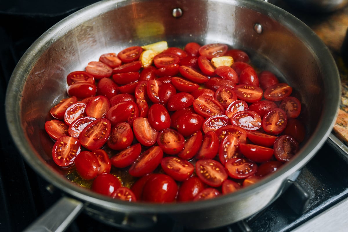 grape tomatoes added to garlic and olive oil in skillet