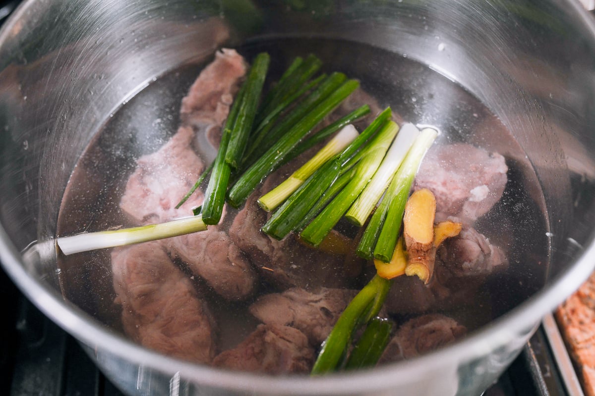 clean pork bones in water with ginger and scallions