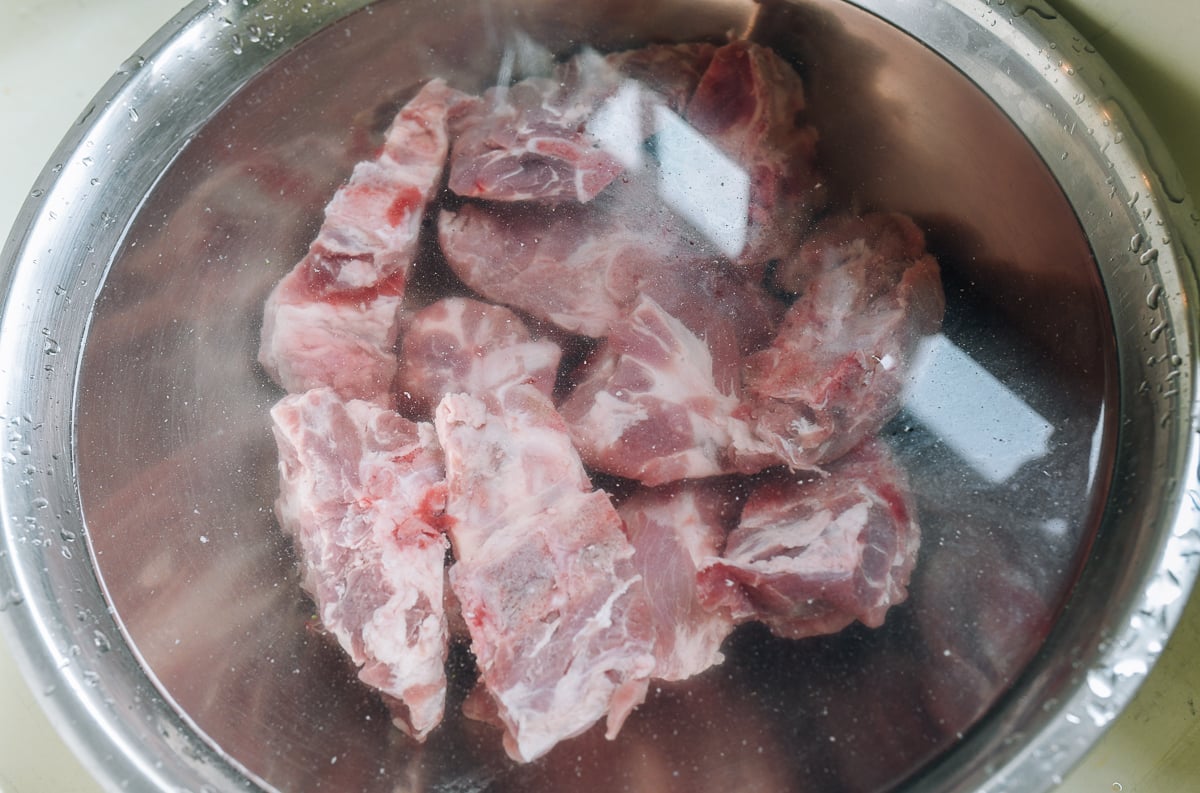 soaking pork neck bones in metal bowl of water