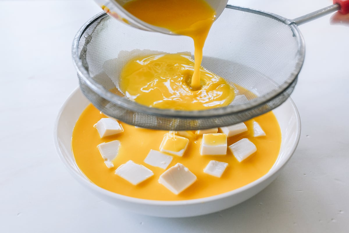 pouring steamed egg mixture over tofu
