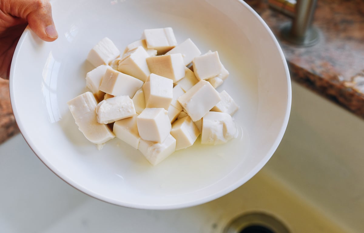 pouring off drained liquid from dish of silken tofu 