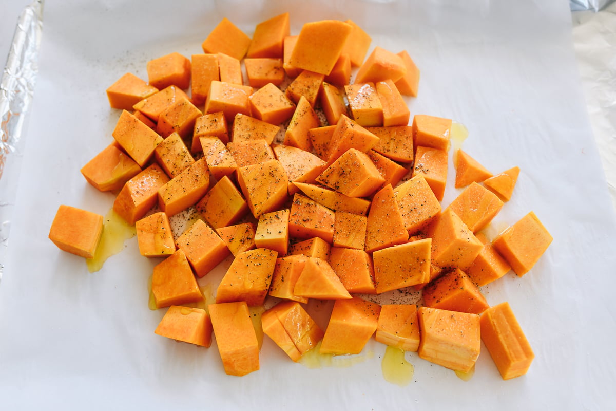 tossing butternut squash with salt, pepper, and olive oil