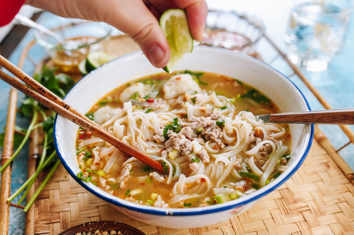 squeezing lime over tom yum noodle soup