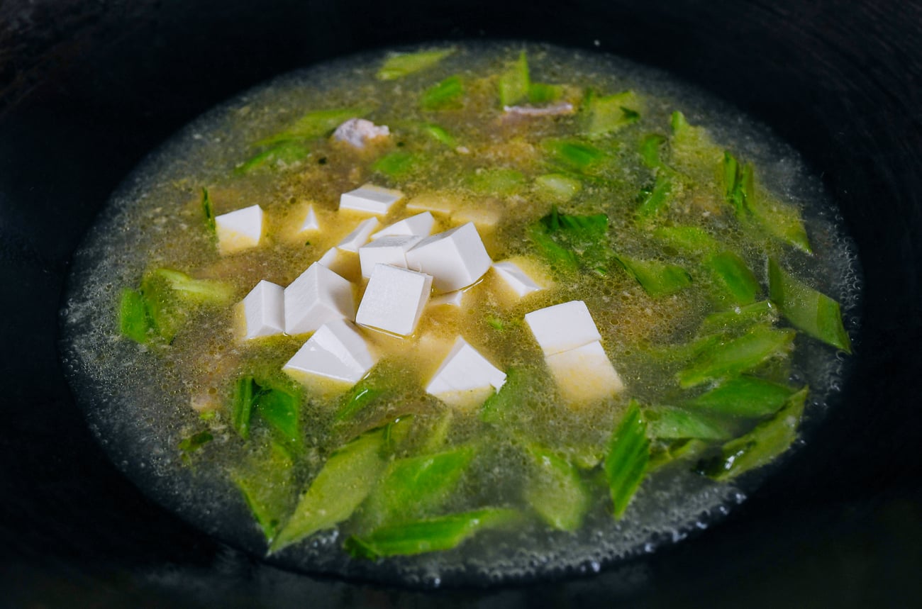 cubed tofu added to pork and mustard green soup
