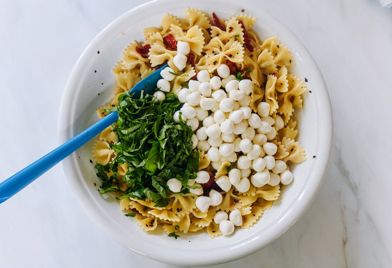 mozzarella pearls and basil added to pasta