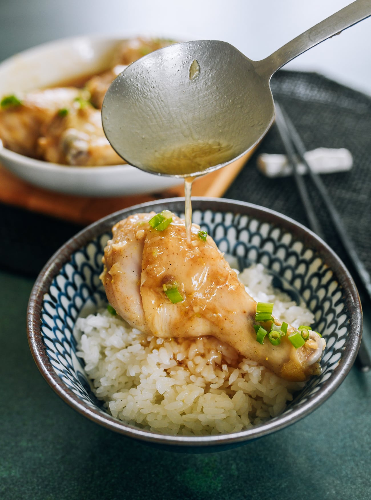 pouring juices onto steamed chicken leg over rice