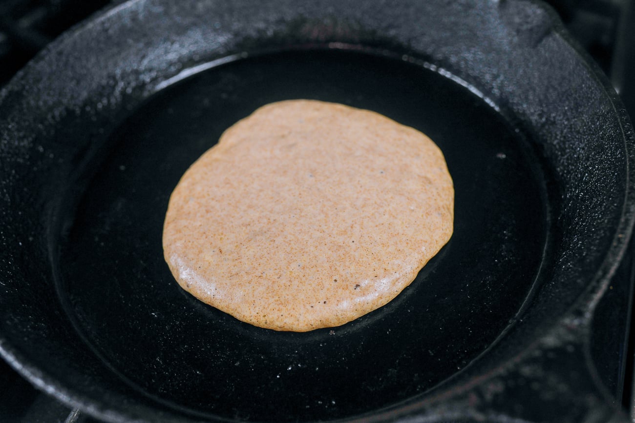 whole wheat pancake cooking in cast iron skillet