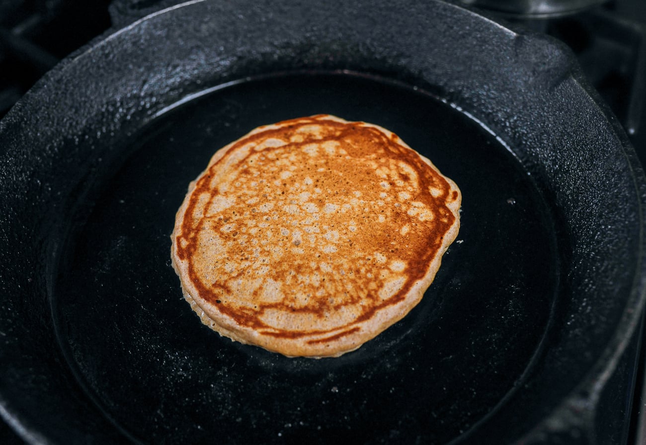 flipped whole wheat pancake in cast iron skillet