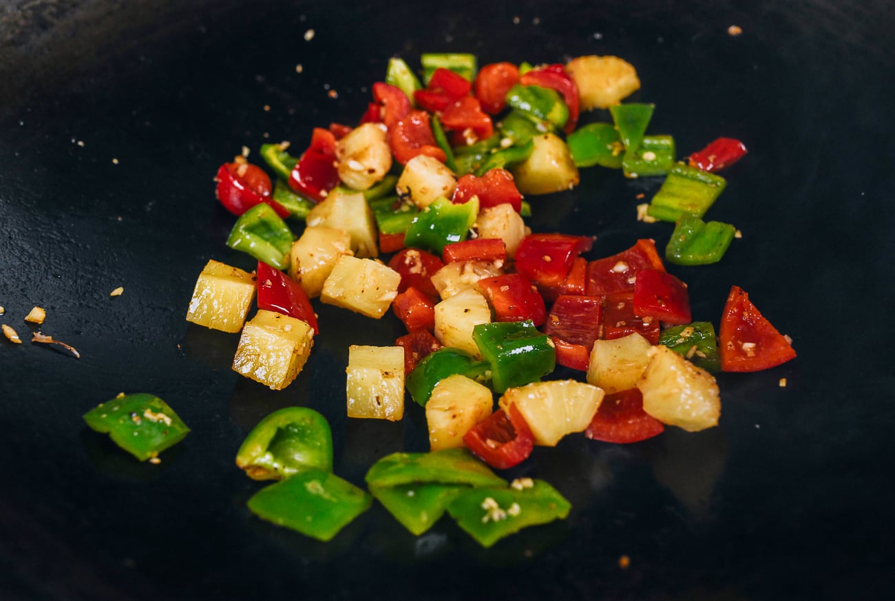 stir-frying peppers and pineapple chunks