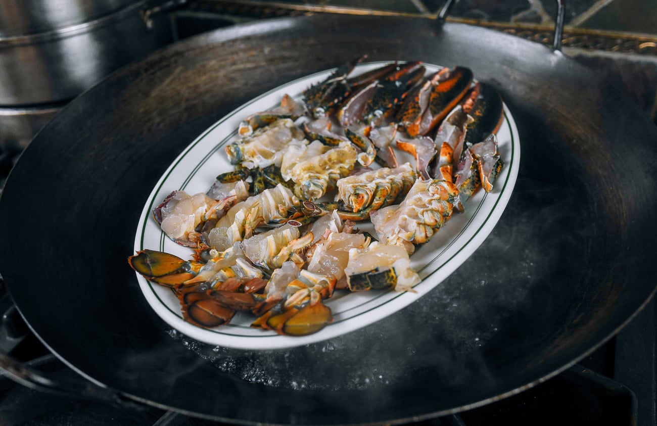 platter of cut lobster in wok for steaming