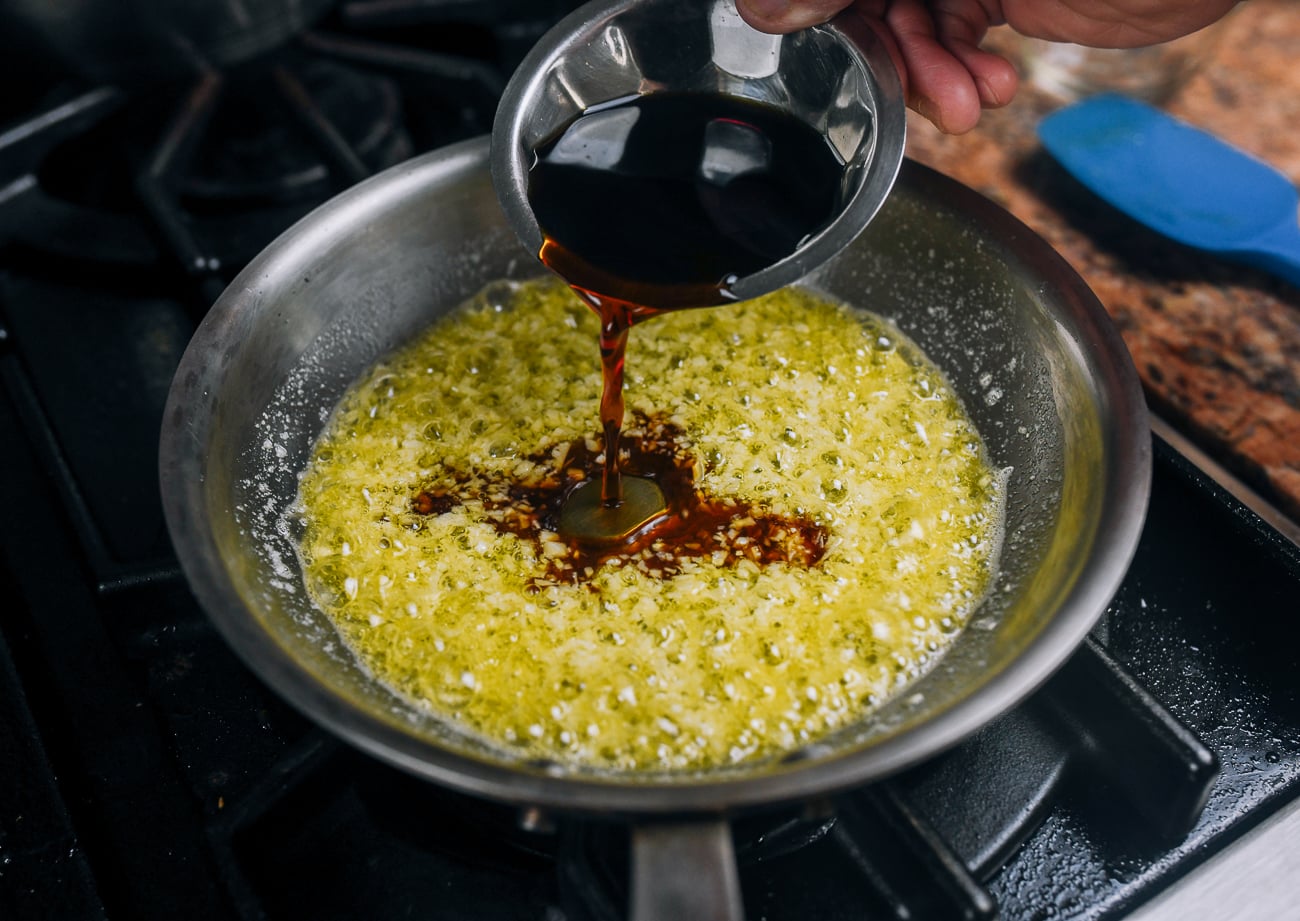 pouring soy sauce and water into pan with butter and garlic