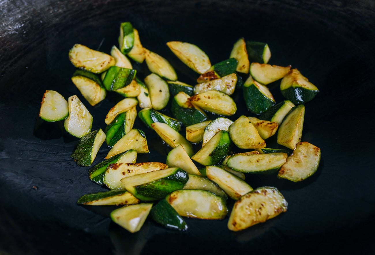 seared zucchini pieces in wok